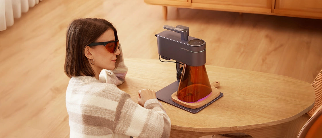 A home DIY enthusiast wearing laser safety goggles to safely observe a LaserPecker engraver in operation.