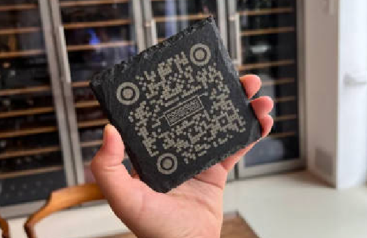 Real User Stories: Hand holding a laser-engraved stone gift (with QR code design) from Rianna and Calvin's Laser Engraving Studio; the studio uses LaserPecker LP5 to create custom engraved gifts for new restaurant openings to build brand recognition.