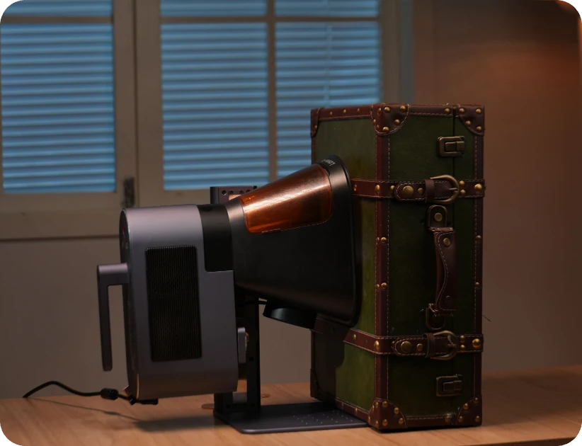LaserPecker LP5 mounted on a stand, positioned to engrave a vintage suitcase surface, demonstrating its capability to process hard-to-reach areas and diverse surfaces (supporting the "Any Angle, Any Surface" feature).