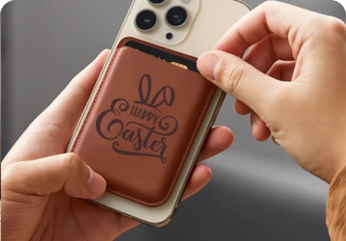 A user holding a phone with a leather card holder attached to the back.