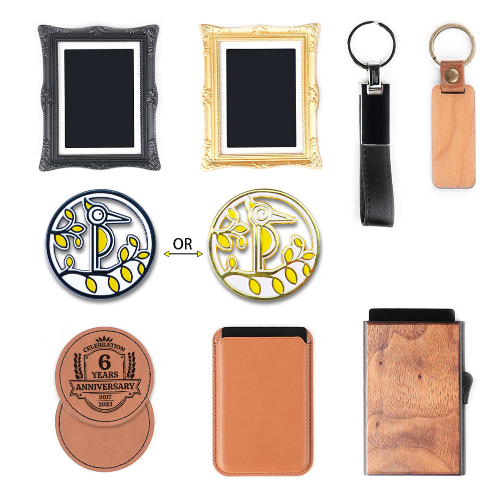 A flat lay of assorted gift and accessory items, including an ornate black picture frame, a gold ornate picture frame, a black leather keychain, a wooden keychain, two interchangeable enamel pins (one black and one gold) featuring a stylized bird design, a leather anniversary coaster set, a tan leather cardholder, and a wooden cardholder.
