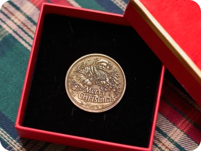 Finished laser-engraved "Merry Christmas" metal coin presented in a red gift box, showcasing the final polished result of LaserPecker LP5's engraving workflow.