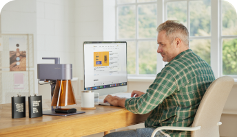 A man using a computer with a LaserPecker machine beside him.