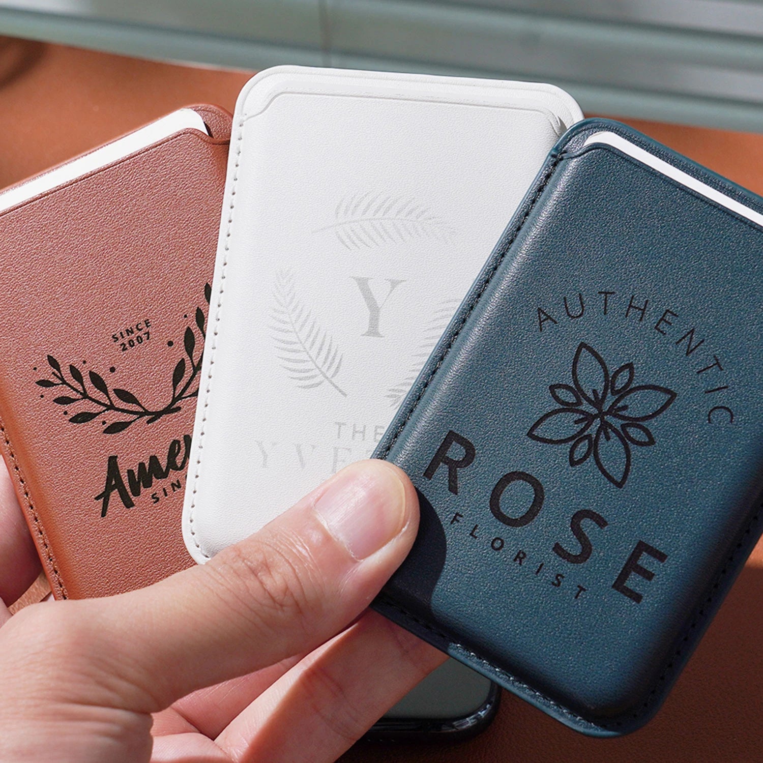 Three slim, faux leather card holders, each laser-engraved with a unique custom design.These compact, stylish card holders demonstrate how laser engraving can transform functional accessories into branded gifts.