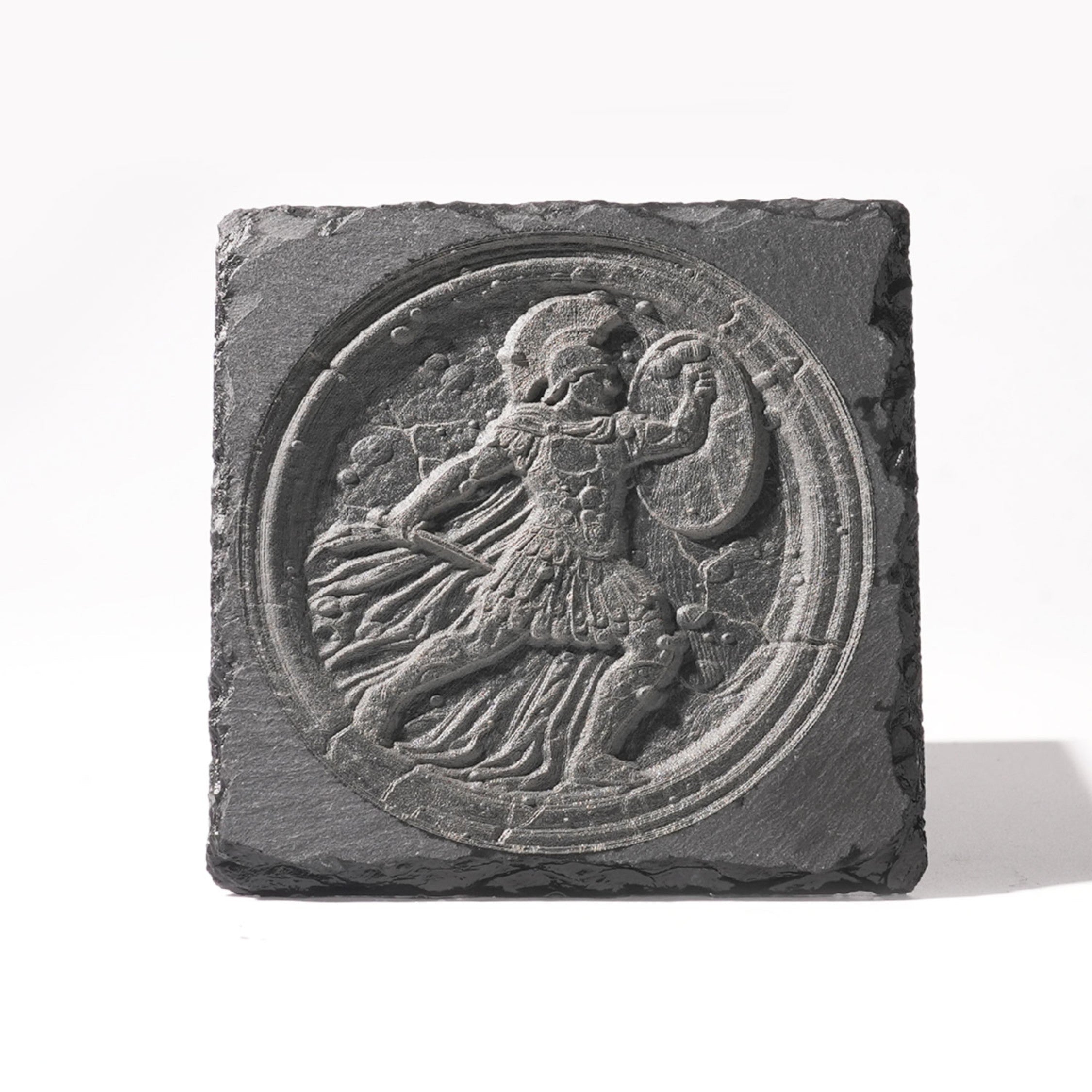 A laser-engraved slate plaque featuring a 3D-style circular design of a classical Greek or Roman warrior, complete with a helmet, shield, and flowing cape. The engraving mimics the texture of ancient stone reliefs, set against the natural rough edges of the slate, creating a durable and historically inspired decorative piece.